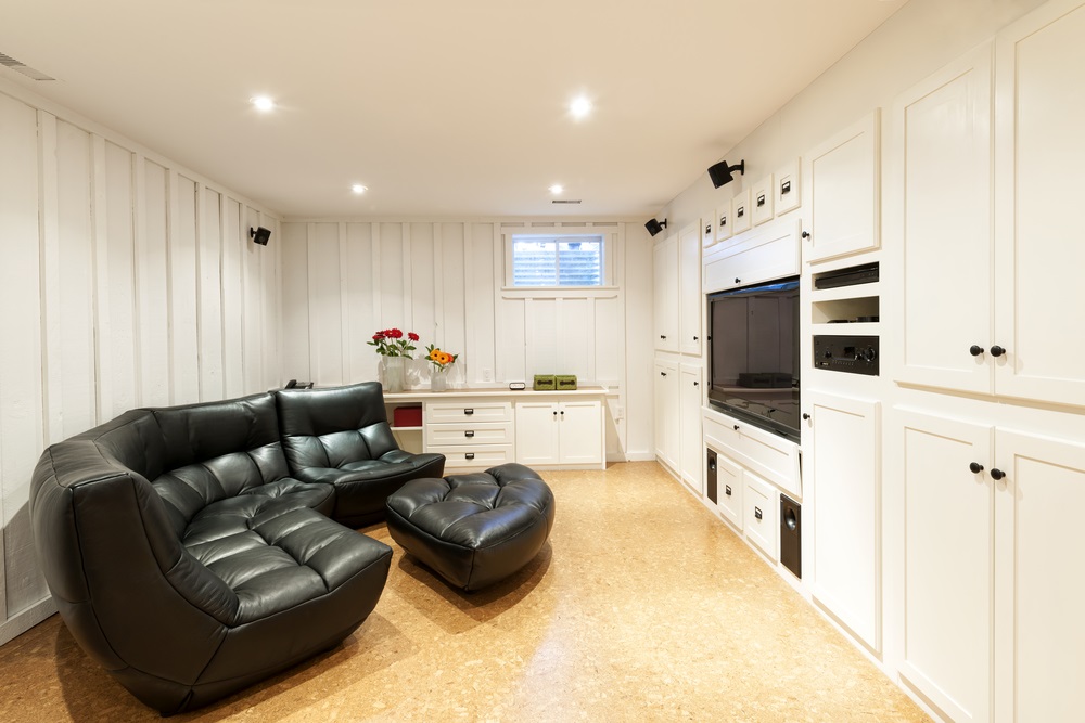 Home Remodeling Cozy media room with black leather sectional sofa, built-in entertainment center, and bright white cabinetry.