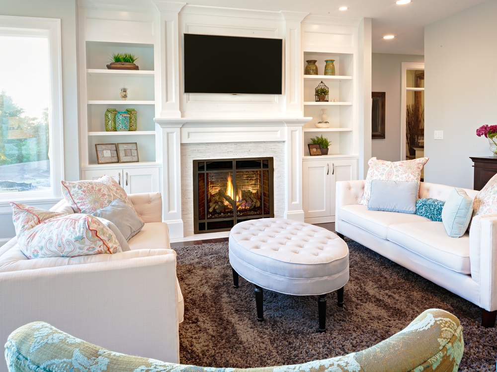 Home remodeling Elegant living room with white sofas, a fireplace, built-in shelves, and soft neutral decor.