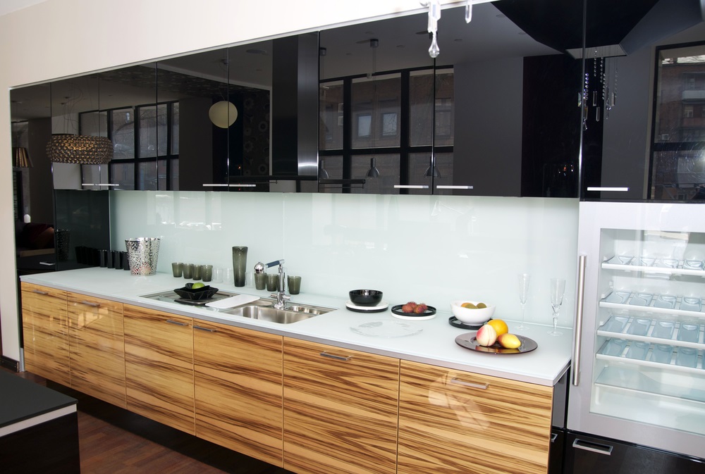 Contemporary kitchen remodeling with high-gloss black cabinets, woodgrain drawers, white countertop, and sleek backsplash for a modern and stylish look.