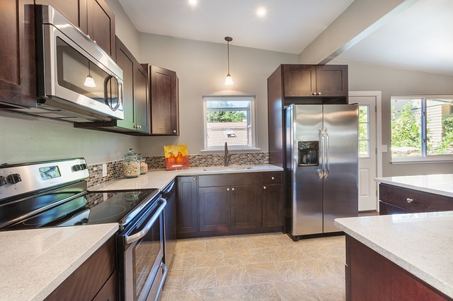 Modern kitchen remodeling with dark wood cabinets, stainless steel appliances, quartz countertops, and a stylish backsplash for a contemporary look.