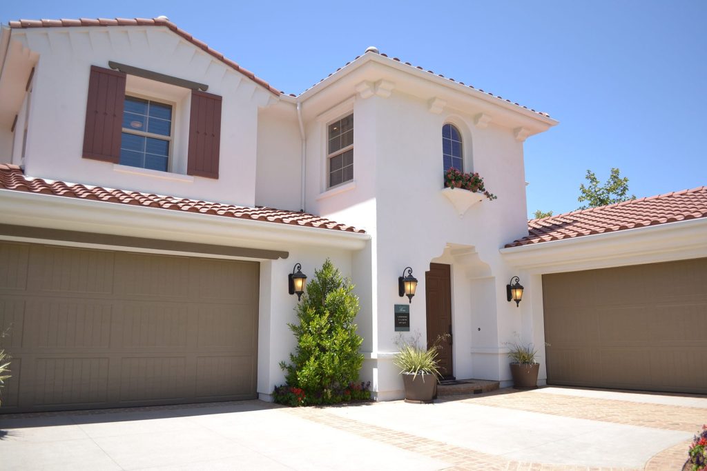 Mediterranean-style home remodeling with stucco exterior, red tile roof, three-car garage, and decorative shutters for a classic and elegant look.