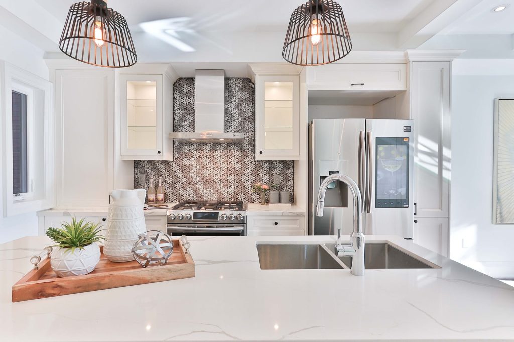 Bright modern kitchen remodeling with white cabinets, patterned backsplash, stainless steel appliances, and elegant pendant lighting for a stylish and airy atmosphere.