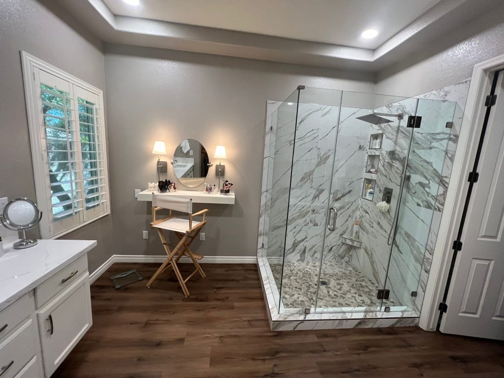 Modern bathroom remodeling with a glass walk-in shower, vanity area, and wood flooring.