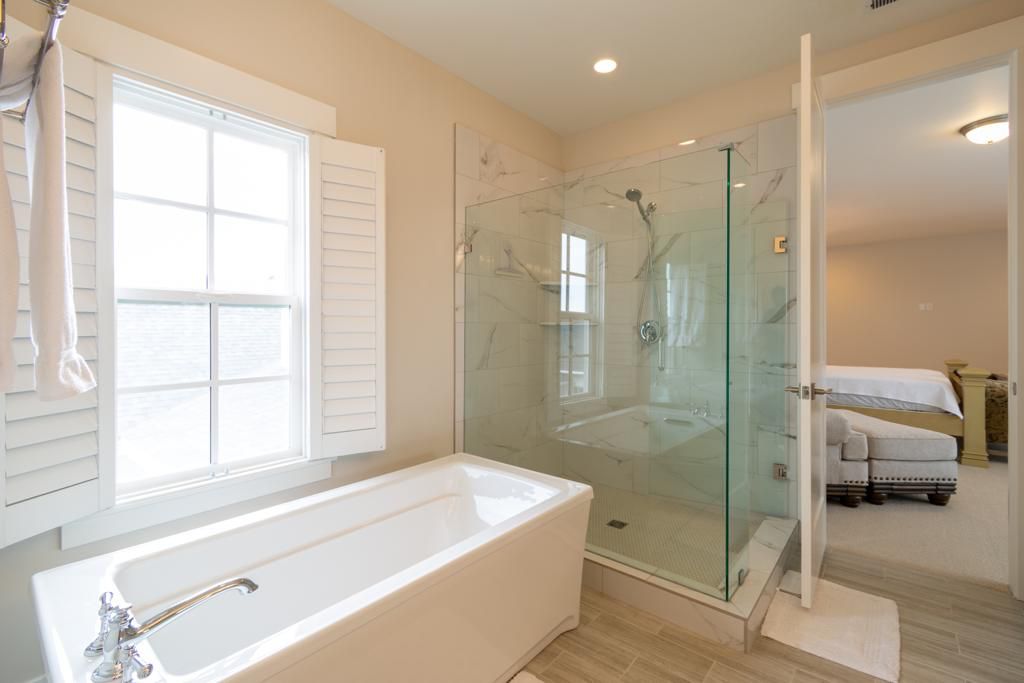 Modern bathroom remodeling with glass shower enclosure, freestanding bathtub, and large window for natural light.