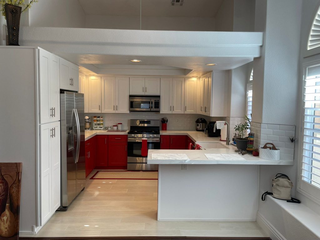 Modern kitchen remodeling with red and white cabinets, stainless steel appliances, marble countertops, and recessed lighting for a bold and stylish design.