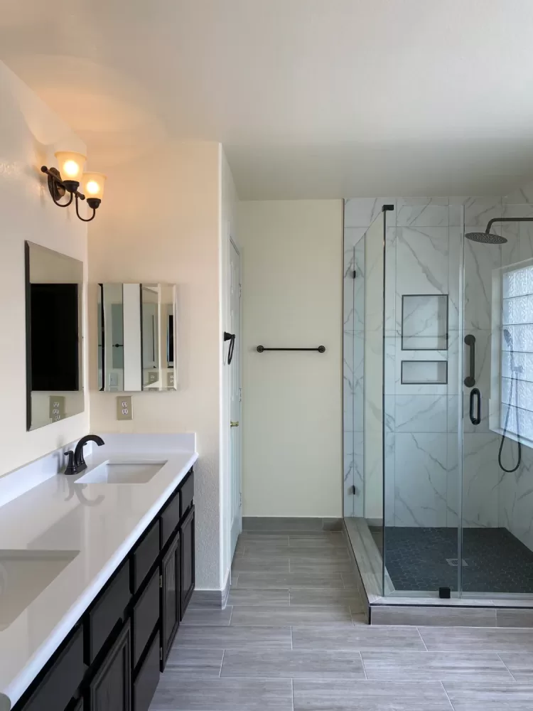 Modern bathroom remodeling with a glass shower, double vanity, large mirror, and light wood flooring for a sleek and contemporary design.