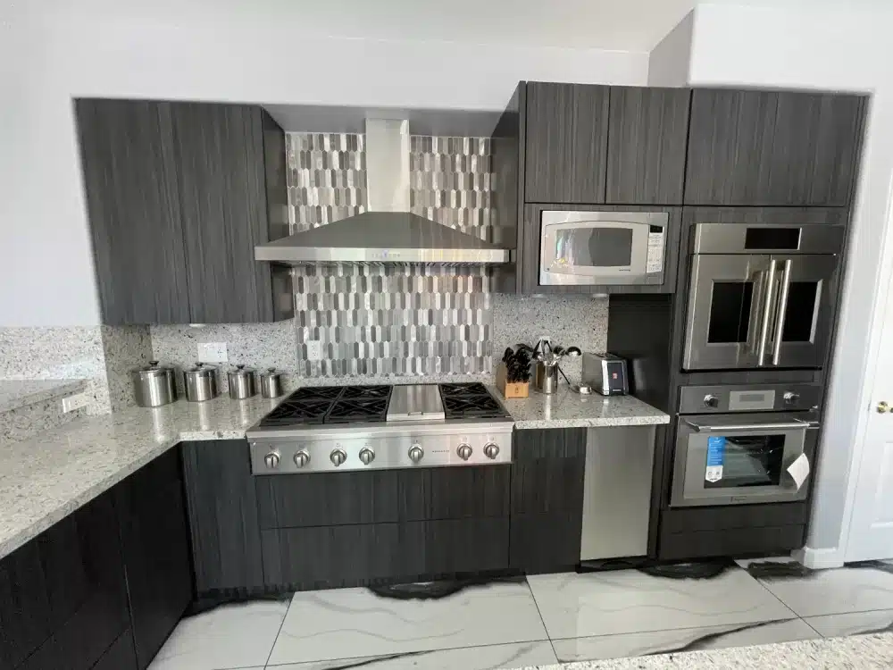 Modern kitchen remodeling with dark cabinets, stainless steel appliances, stylish backsplash, and granite countertops for a sleek and contemporary look.