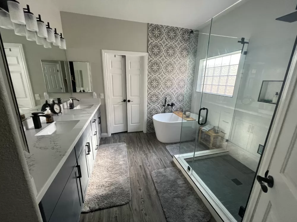 Modern bathroom remodeling with glass shower, freestanding tub, double vanity, and decorative accent wall.