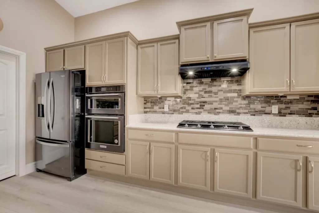 Modern kitchen remodeling design with beige cabinets, stainless steel appliances, and a mosaic tile backsplash for a stylish and functional cooking space.