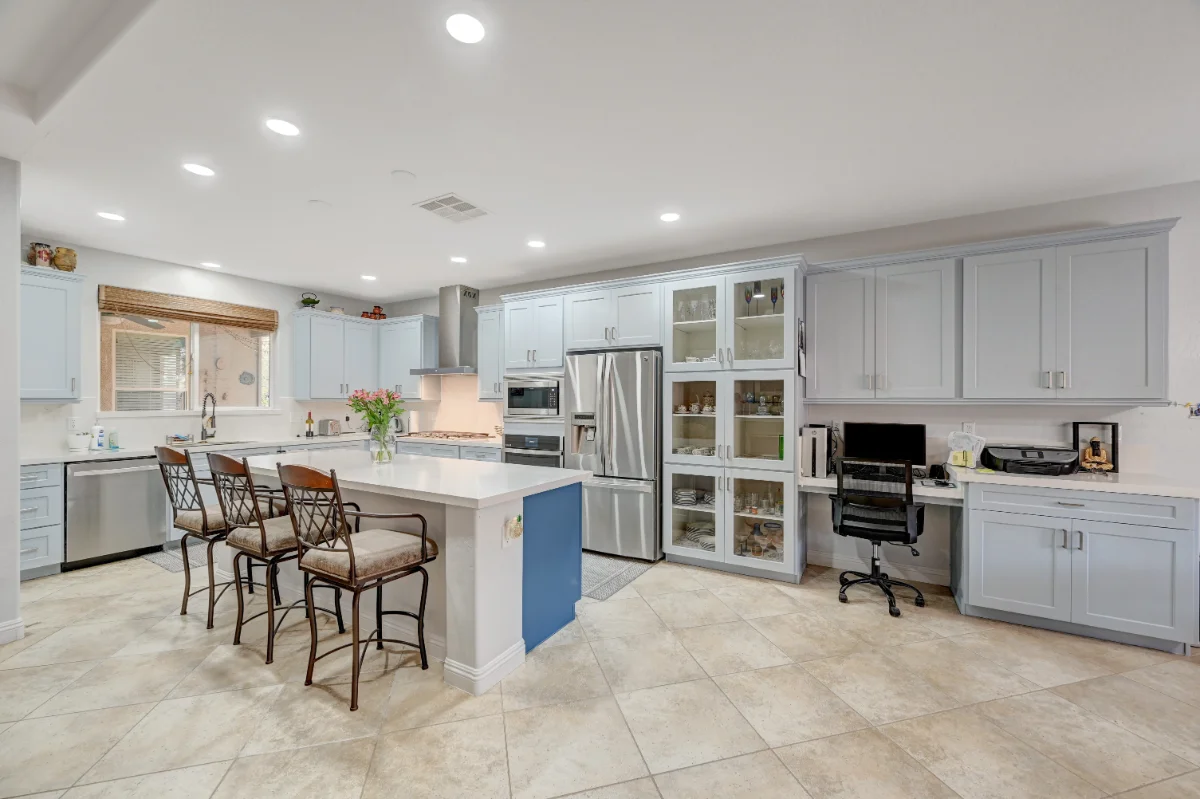 Spacious modern kitchen remodeling with island seating, built-in home office, stainless steel appliances, and light gray cabinets for a functional and stylish space.