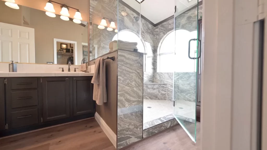 Elegant bathroom remodel featuring a luxurious marble shower, modern double vanity with stylish fixtures, and sophisticated lighting.