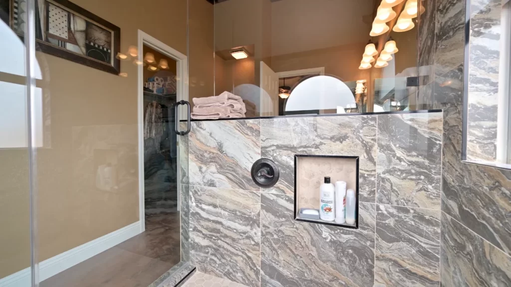 Bathroom remodeling Luxury walk-in shower with marble tile, built-in shelving, and glass enclosure.